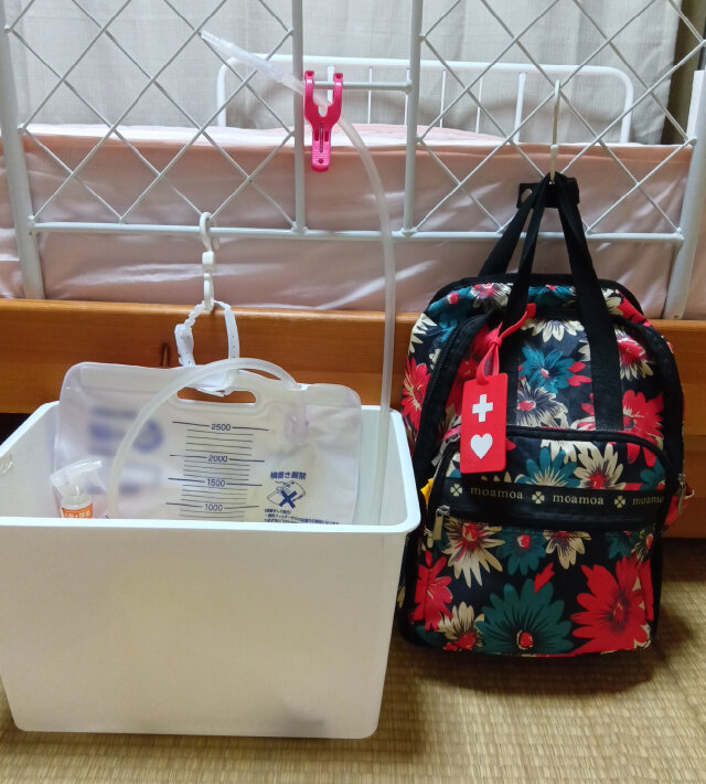 蓄尿バッグと、装具が入った災害用のバッグをベッド柵に並べている様子